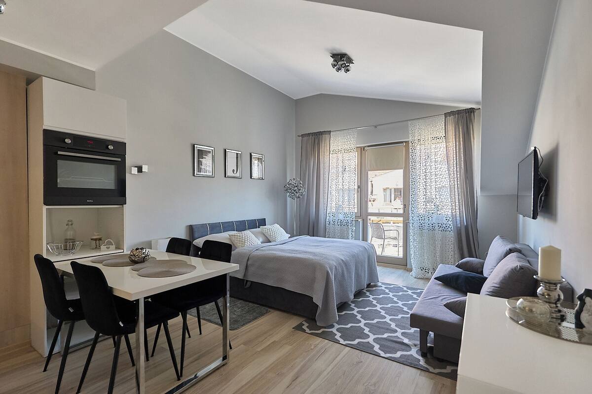 Ein modernes Schlafzimmer mit Bett, Schreibtisch und einer Küchenzeile.