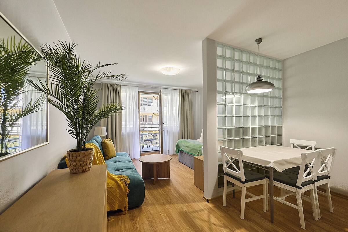 Ein gemütlicher Wohnbereich mit einer Couch, einem Esstisch und einem Blumentopf.