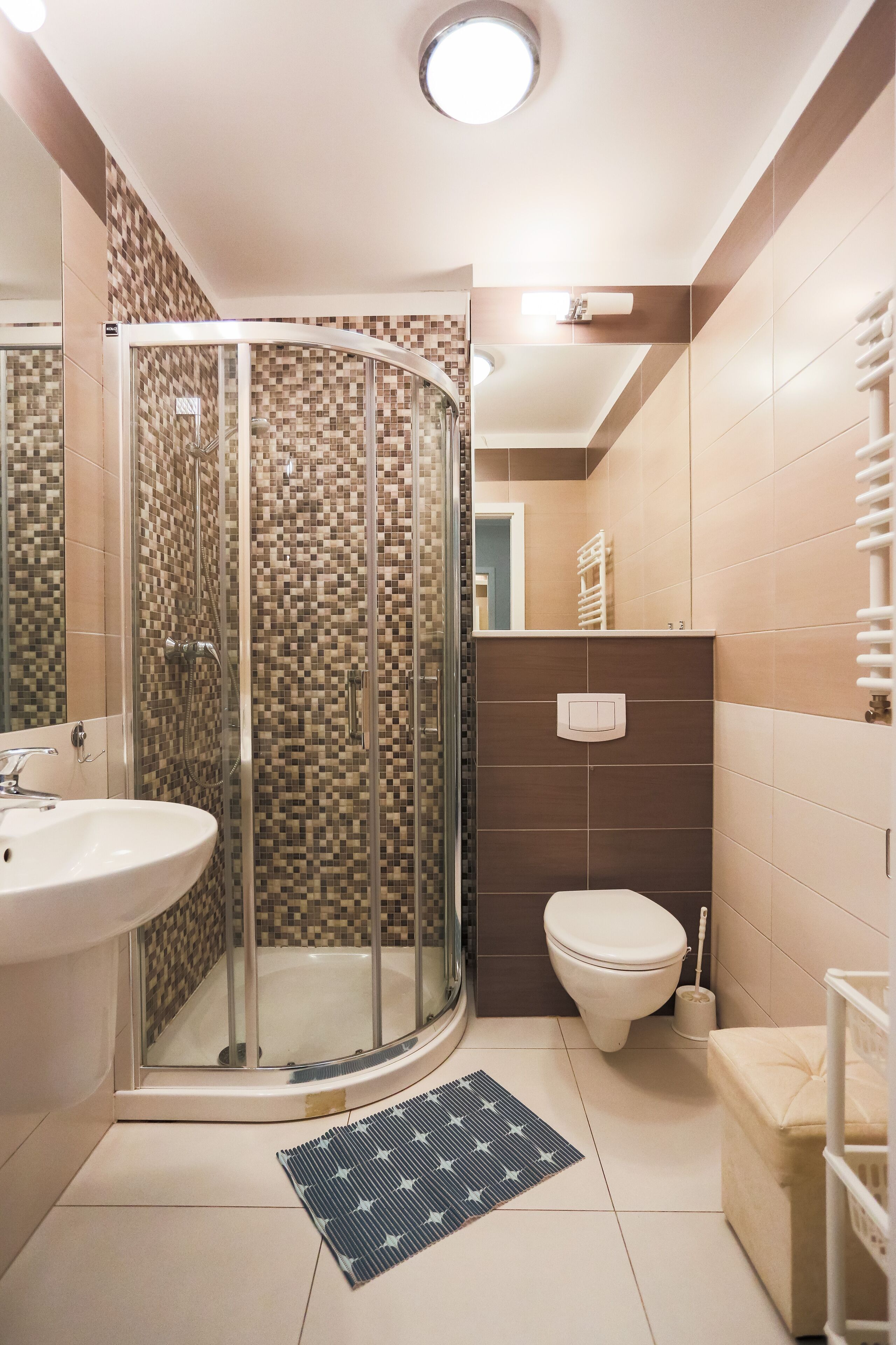 Ein Badezimmer mit Duschkabine aus Glas, Toilette, Waschbecken und Handtuchhalter.