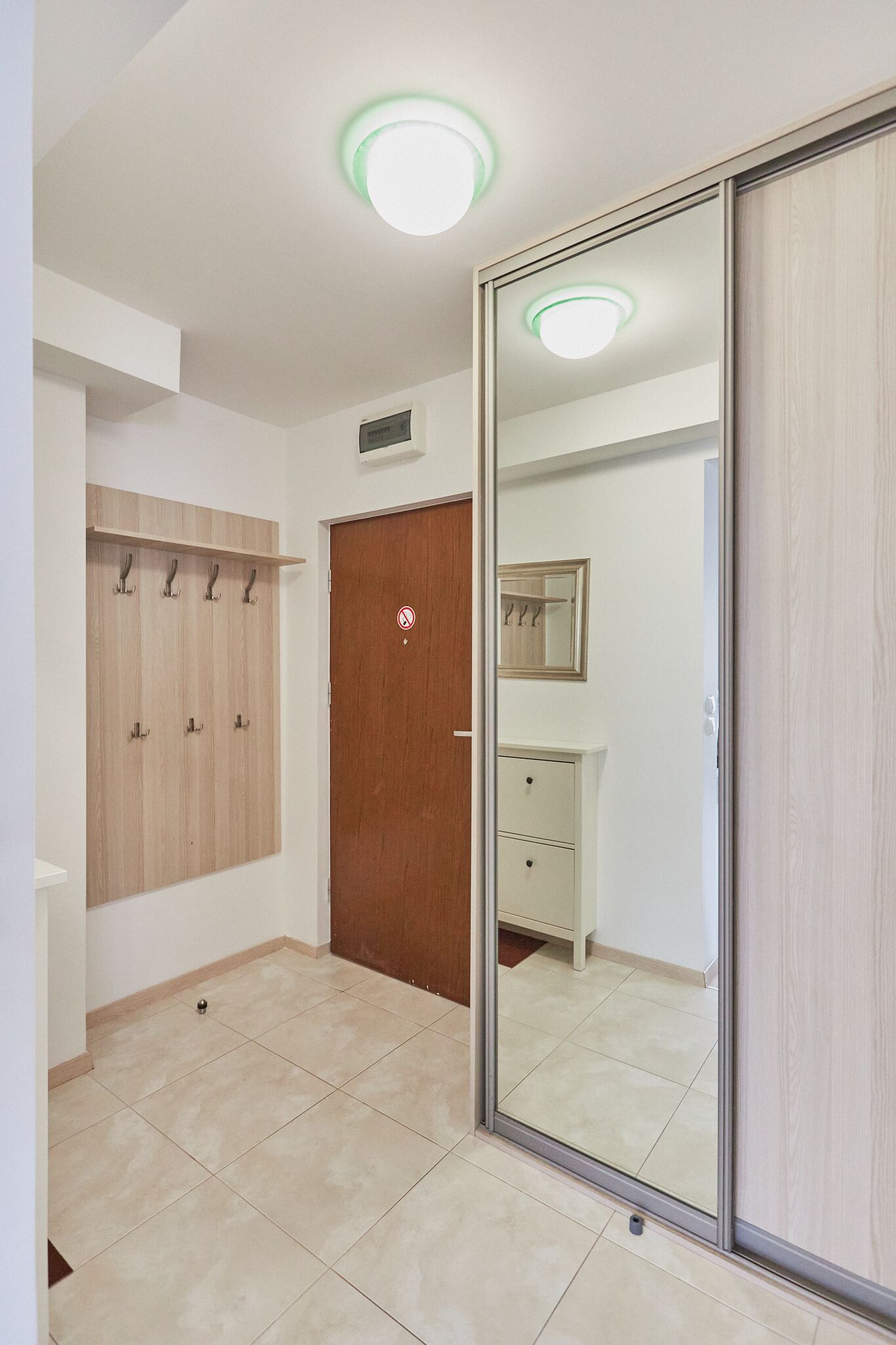A room with a wooden wardrobe, a mirror, and a tiled floor.
