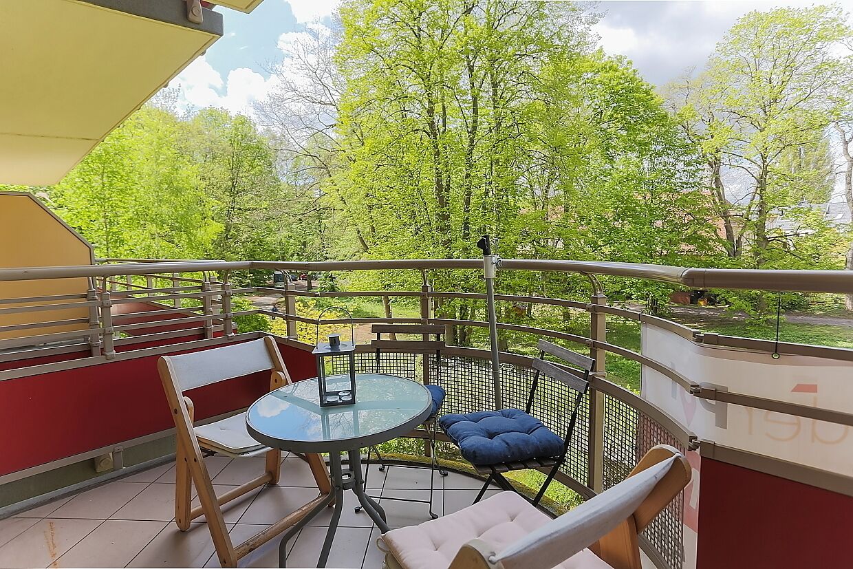 A balcony with a round table, chairs, and a blue cushion.
