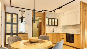 A modern kitchen with wooden cabinets, a built-in oven, and a marble countertop.
