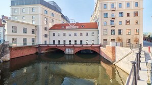 Un bâtiment surmonté d’un pont en briques rouges qui enjambe un canal, et qui porte le nom de « MEYN-MARIA ».