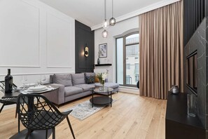 A modern living room with a sofa, a coffee table, and a dining area with chairs and a table set for a meal.