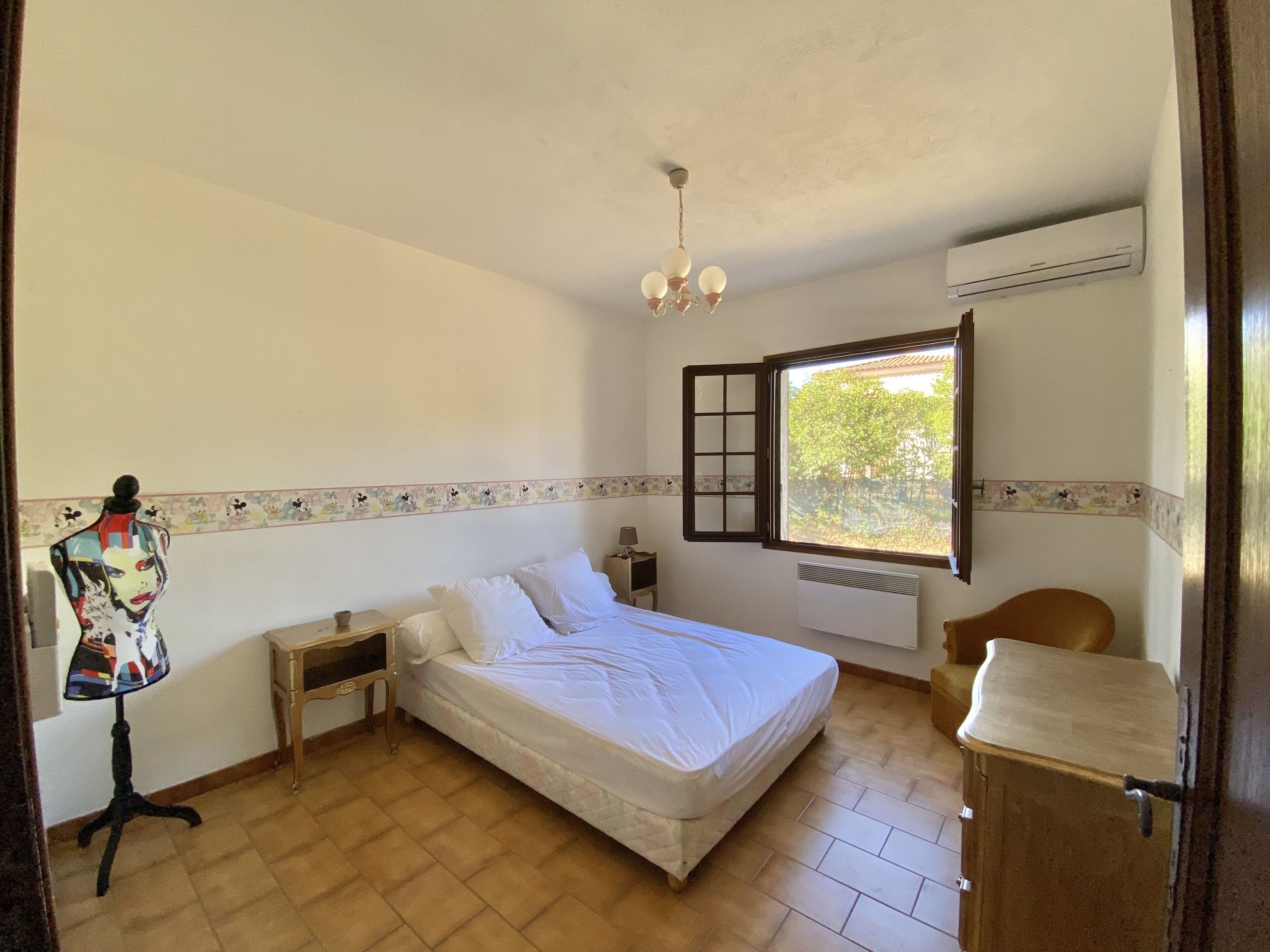 A bedroom with a bed, a dresser, a mannequin, a window, and a ceiling fan.