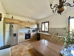 Une cuisine moderne avec des meubles en bois, des appareils en acier inoxydable, un grand îlot central et une fenêtre offrant une belle vue.