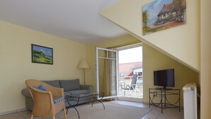 A living room with a sofa, a chair, a TV, and a painting on the wall.