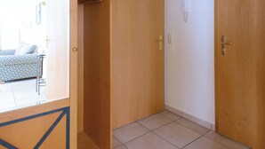 A room with a wooden wardrobe, a tiled floor, and a door.
