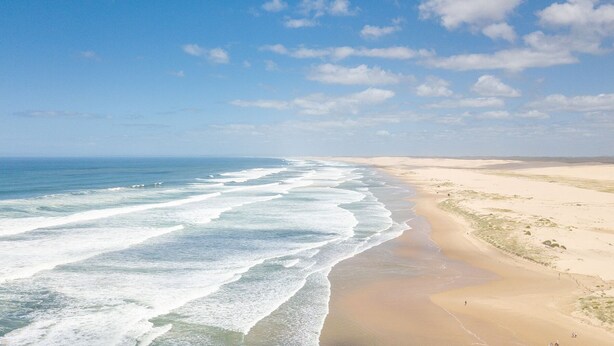 Une plage avec des vagues, du sable et un ciel dégagé.