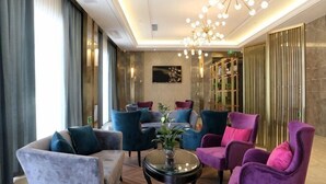 A modern lounge with plush seating, a chandelier, and a large mirror.