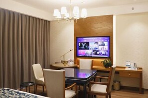 A hotel room with a dining table, chairs, a TV mounted on the wall, a desk, and a bed. - GEM Hotel (Jianhu Ouboliya Zunyuan) (Jianhu)