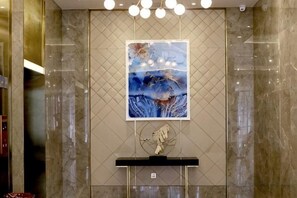A lobby with a marble wall, a framed artwork, and a reception desk. - GEM Hotel (Jianhu Ouboliya Zunyuan) (Jianhu)
