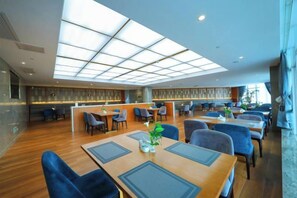 A spacious dining area with high ceilings and natural light, featuring multiple tables and chairs.