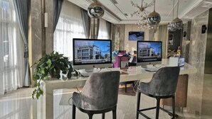 A modern kitchen with two large monitors, a marble countertop, and bar stools.