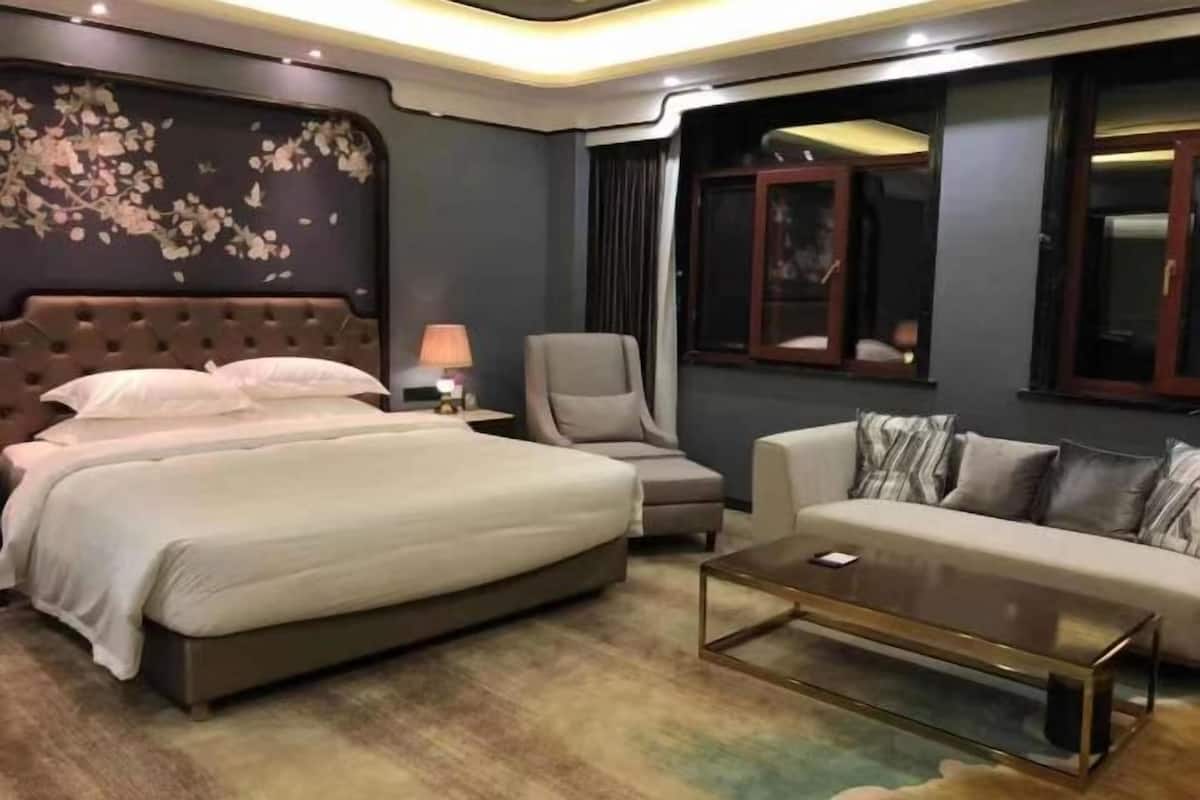 A hotel room with a large bed, a sofa, a chair, and a coffee table.