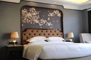 Una cama grande con cabecera capitonada, dos lámparas de noche y una obra de arte floral colgada en la pared.