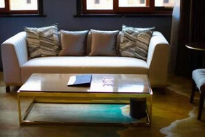 A white sofa with patterned cushions, a glass coffee table, and a small side table. - Lihu Hotel (Kaiyuan)
