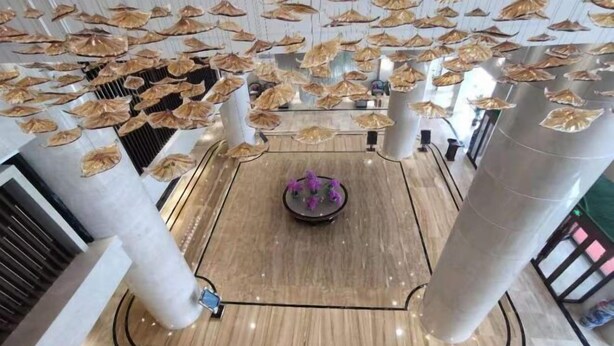 Un hall d’entrée spacieux, doté d’un sol en marbre poli, de grandes colonnes et d’un élément décoratif central.