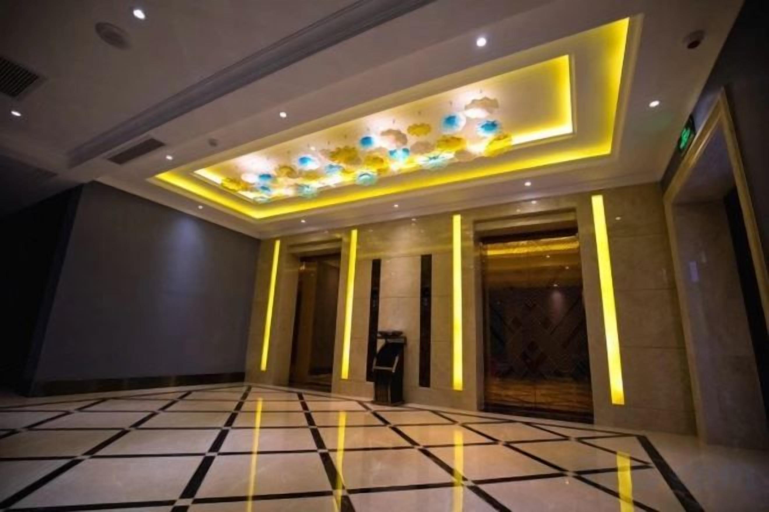 A hotel lobby with a checkered floor, a reception desk, and a decorative ceiling light fixture.