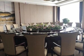 Een vergaderzaal met een ronde tafel, stoelen en een bloemstuk.
