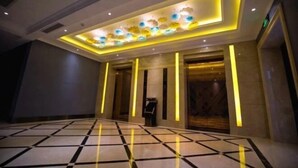 Un hall d’hôtel avec un sol à carreaux, un comptoir d’accueil et un plafond décoratif agrémenté de panneaux lumineux.