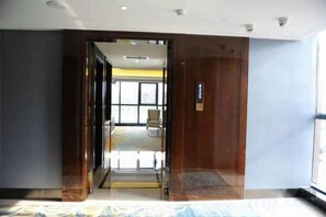 Een hotelkamer met een groot bed, een houten deur en uitzicht op buiten.