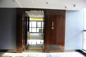 Habitación de hotel con una cama grande, una puerta de madera y vistas al exterior.