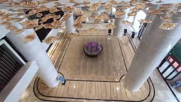 Eine geräumige Lobby mit einer zentralen Fontäne, hohen Decken und Säulen.