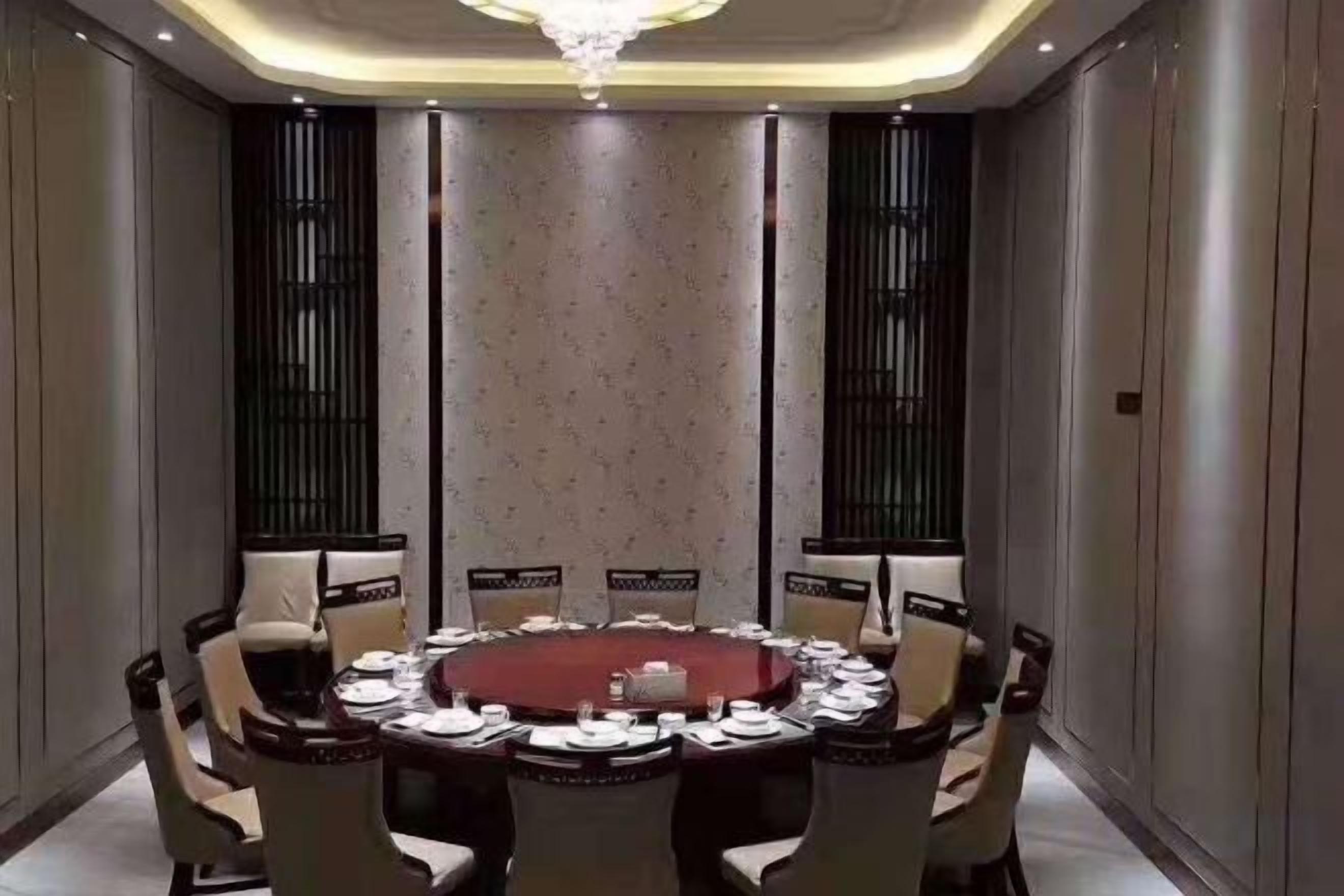 A conference room with a round table, chairs, and a chandelier.