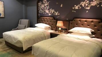 Ein Hotelzimmer mit zwei Betten, einem Nachttisch, einer Lampe und einem Sessel.