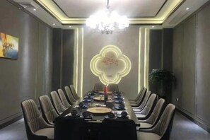 Une salle de conférence avec une longue table, des chaises et un lustre.