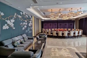 Un moderno vestíbulo de hotel con sofá, mesa de comedor y sillas, y una pared decorativa con motivos florales.