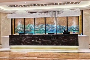 A reception desk with a modern design, a large wall painting, and a decorative ceiling feature.