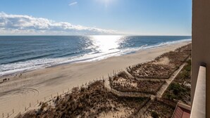 A beach with a clear sky, the sun shining, and a fence running along the shore. - New Listing! Beautiful ocean front views, just steps to the beach. (Ocean City)