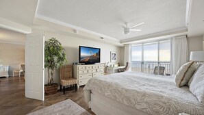 A spacious bedroom with a large bed, a television, a desk, and a balcony with a view. - New Listing!  Large luxury condo on the boardwalk with pool! (Ocean City)