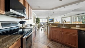 A modern kitchen with wooden cabinets, a built-in microwave, and a large island with a sink. - New Listing!  Large luxury condo on the boardwalk with pool! (Ocean City)