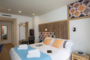A hotel room with a bed, bedside table, and a mirror.