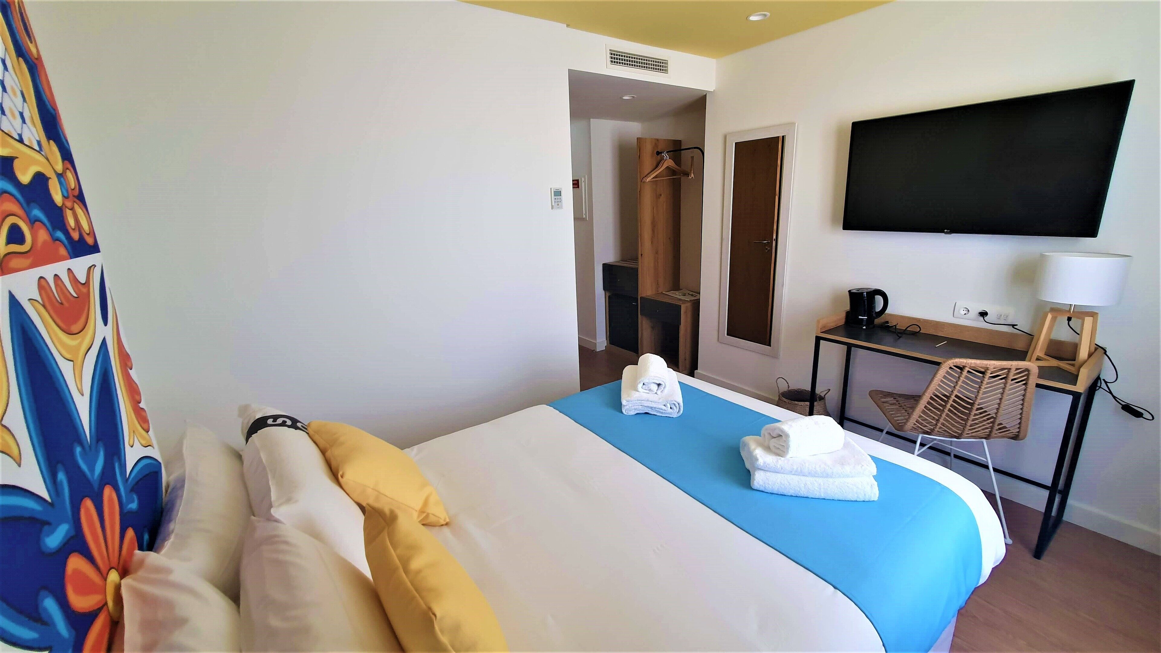 Une chambre d’hôtel équipée d’un lit, d’un bureau, d’une télévision et d’un espace douche.