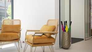 Two yellow cushioned chairs with metal frames, a wicker chair, and a decorative vase with umbrellas. - Casual Raizes Porto Hotel by Casual Hoteles (Porto)