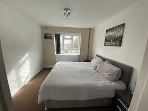 A bedroom with a bed, a window, a radiator, a picture on the wall, and a ceiling light. - Lovely 2-bed Apartment in Solihull (Solihull)