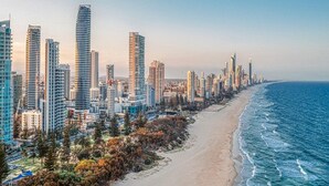 A coastal cityscape with high-rise buildings along a beach.