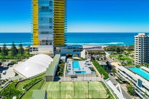 Un hôtel moderne doté d’une grande piscine, d’un court de tennis et offrant une vue sur l’océan.