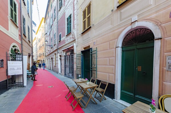 A narrow street with a red carpet leading to a building with a green door and a signboard.