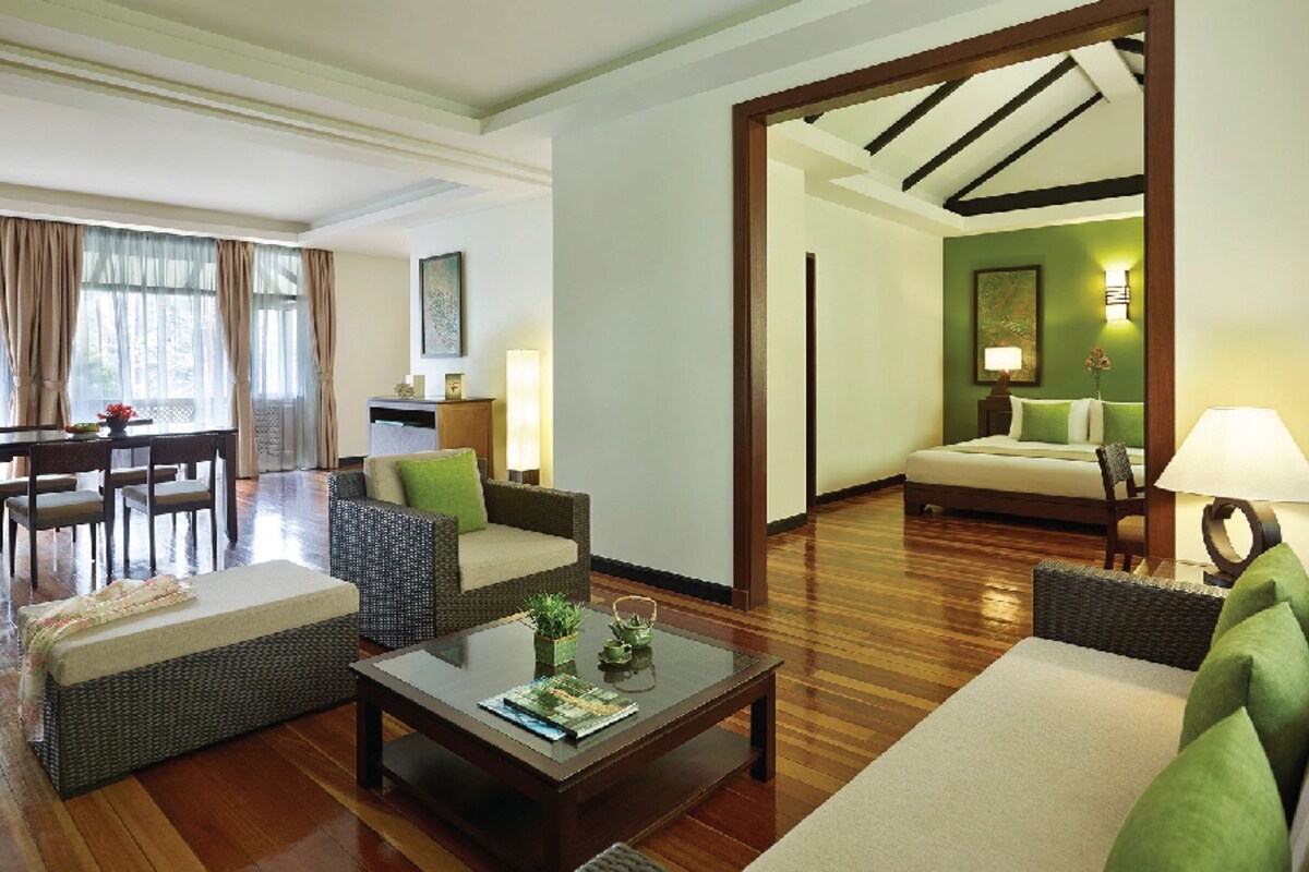 A hotel room with a living area, a dining area, and a bedroom.