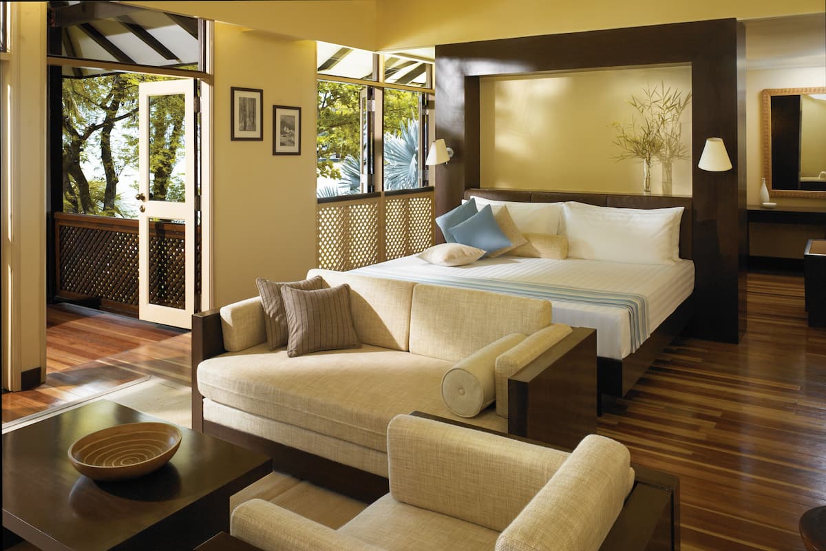 A hotel room with a bed, a sofa, a coffee table, and a view of the outdoors.