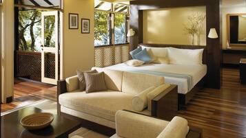 A hotel room with a bed, a sofa, a coffee table, and a view of the outdoors.