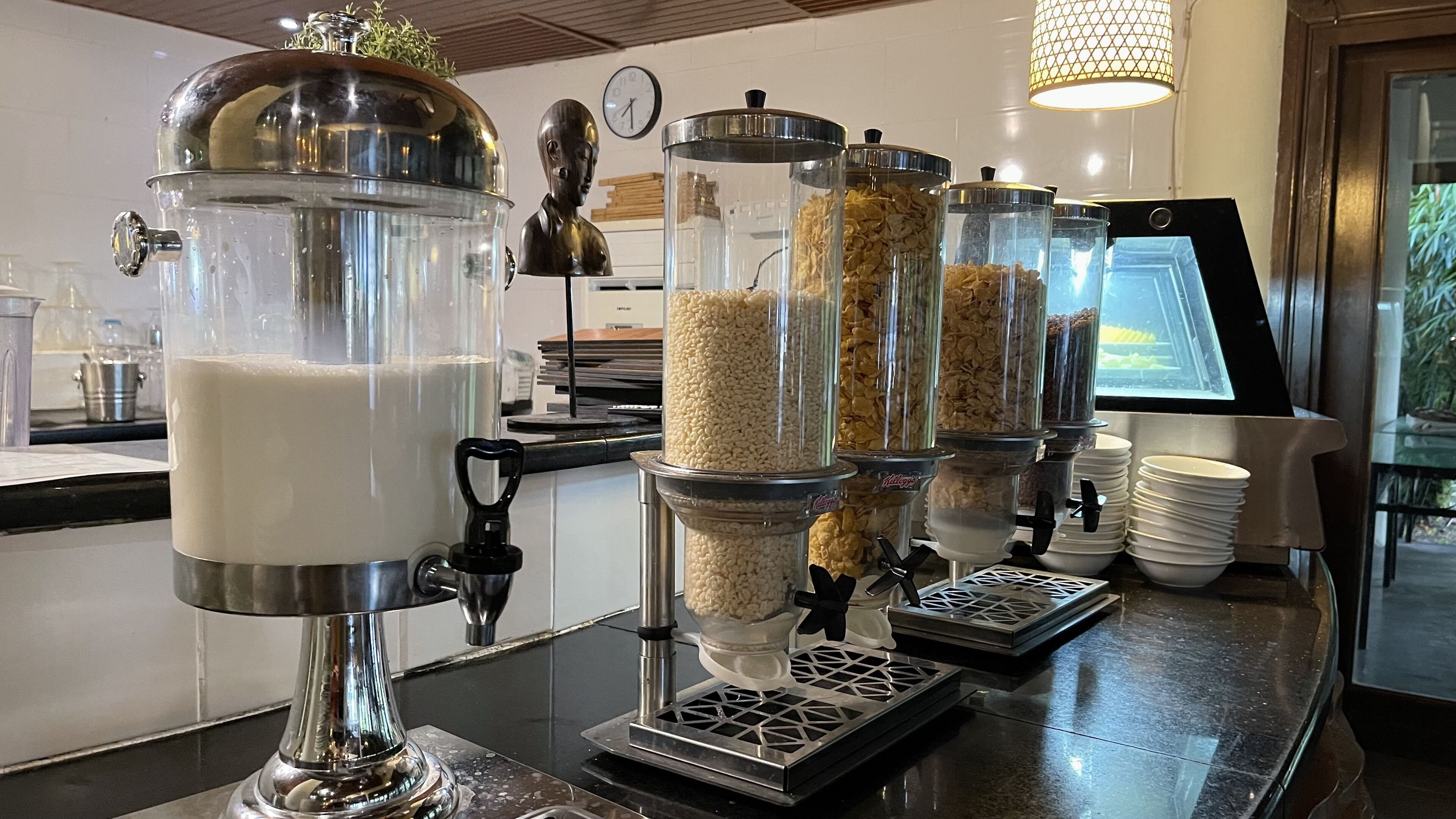 A self-serve beverage station with milk, cereal, and granola dispensers.