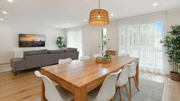A modern living room with a wooden dining table, white chairs, a grey sofa, and a large window with sheer curtains. - Lansell Retreat in Cowes (Cowes)