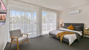 A bedroom with a bed, a chair, a nightstand, and a window with sheer curtains. - Lansell Retreat in Cowes (Cowes)