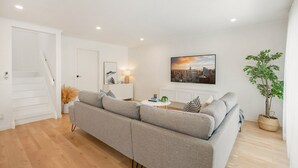 A modern living room with a grey sofa, a coffee table, and a cityscape painting on the wall. - Lansell Retreat in Cowes (Cowes)